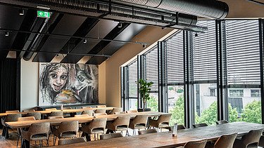 Photo of an interior of the Maisel brewery in Bayreuth. You can see a furnished meeting room with a picture of a person and a wolf.
