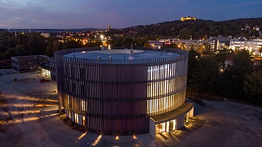 Nachtaufnahme des Globe Theaters in Coburg. Zu sehen ist ein rundes Gebäude aus Holz.