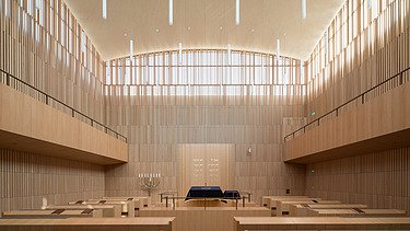 Foto eines Innenraumes einer Synagoge. Holzwände und Holzdecken und Holzbänke sind zu sehen