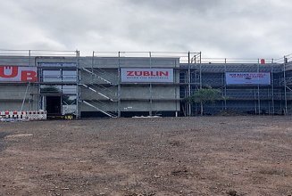 Foto von der Baustelle Schule Emleben von außen. Man sieht Gerüstbanner mit ZÜBLIN-Logo am Grüst hängen.