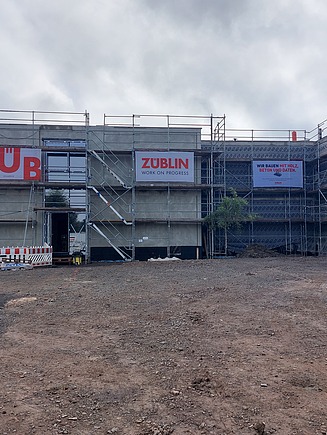 Photo of the Emleben school construction site from the outside. You can see scaffolding banners with the ZÜBLIN logo hanging on the scaffolding.
