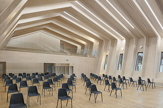 Ingenieurholzbau und Freiformflächen von ZÜBLIN Timber. Projekt Metropolitan School Berlin Foto des Bühnenraumes in der Metropoliton School in Berlin. Zu erkennen ist eine gewölbte Dachkonstruktion.