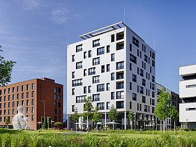 Photo of the SKAIO Stadtsiedlung building in Heilbronn. You can see a multi-storey, white building.